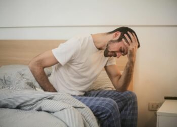 Young man in sleepwear suffering from headache in morning
