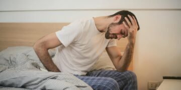 Young man in sleepwear suffering from headache in morning